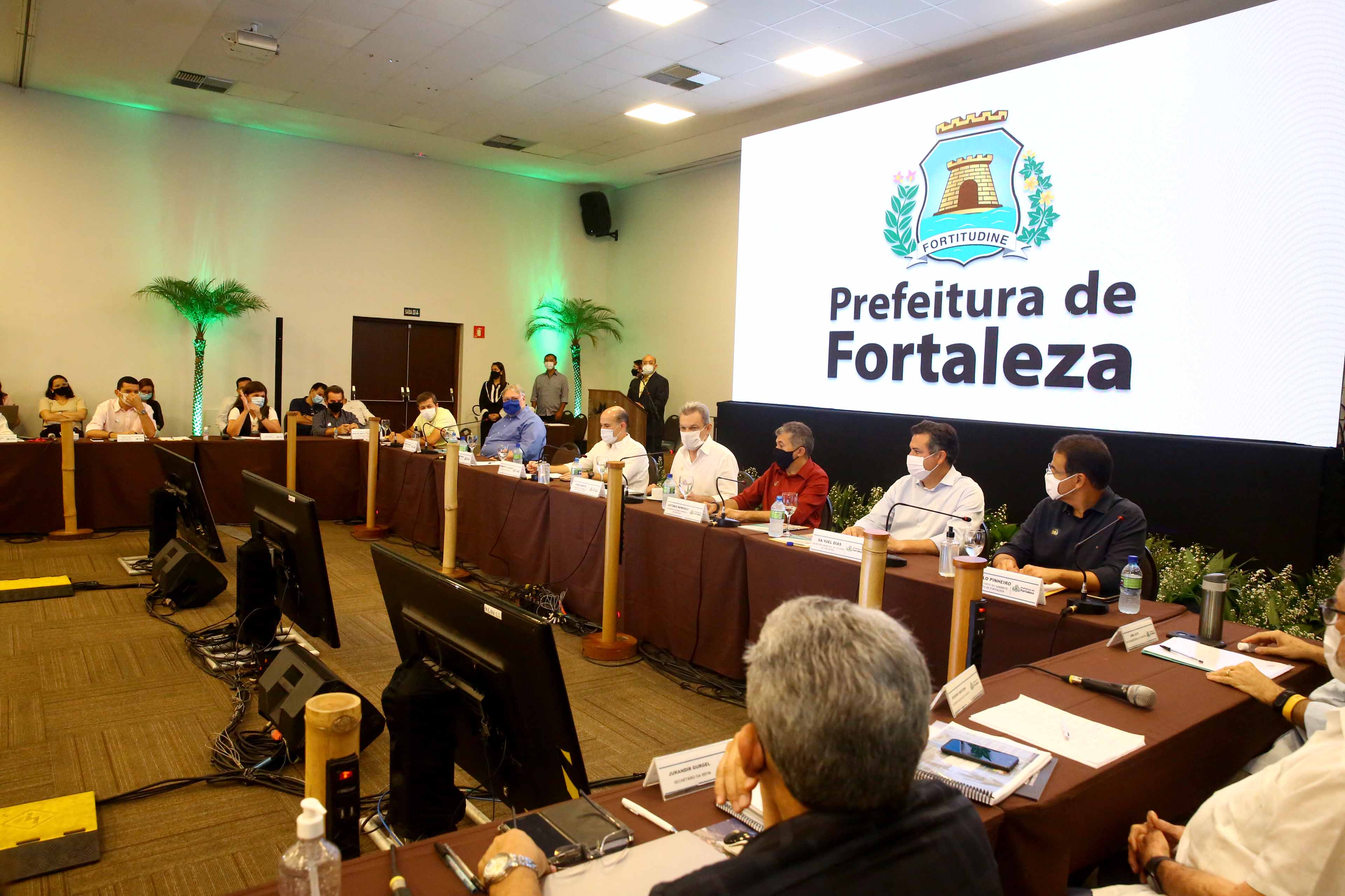 prefeito e José Sarto sentados em frente a uma grande mesa disposta em quadrado com vários secretários sentados ao lado